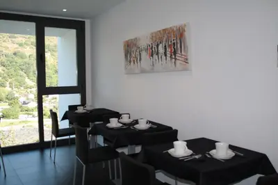a dining room with black tables and chairs and a painting at Hostal Tres Campanas in Villafranca del Bierzo