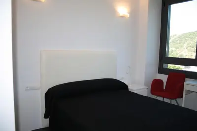a bedroom with a black bed and a red chair at Hostal Tres Campanas in Villafranca del Bierzo