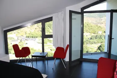 a bedroom with red chairs and a large window at Hostal Tres Campanas in Villafranca del Bierzo