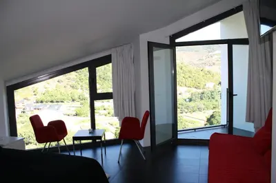 a room with red chairs and a large window at Hostal Tres Campanas in Villafranca del Bierzo
