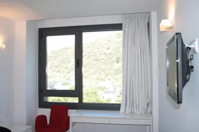 a window with a red chair next to a desk at Hostal Tres Campanas in Villafranca del Bierzo