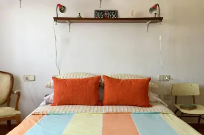 a bed with orange pillows and a clock on the wall at Casa Rural Picape in Pedre