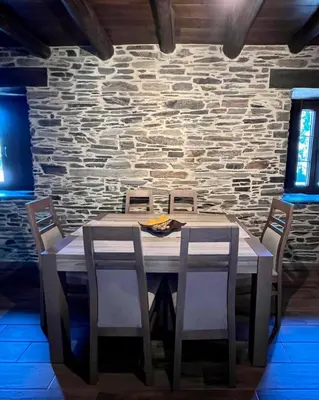 a wooden table with chairs and a stone wall at Casa A Poza in Samos