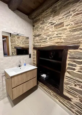a bathroom with a sink and a stone wall at Casa A Poza in Samos