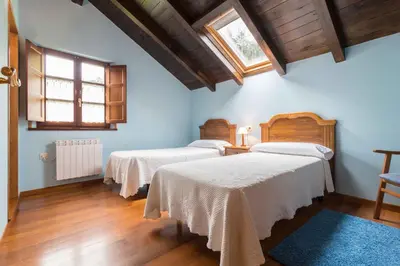 two beds in a room with blue walls and wooden floors at apartamentos castrovaselle nº2 in Castrovaselle