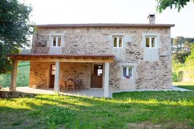 a stone house with a porch and a table at A Quinta Das Maceiras in San Miguel de Castro