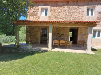 a patio of a stone house with a table and chairs at A Quinta Das Maceiras in San Miguel de Castro