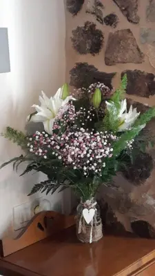 a vase filled with white flowers on a table at A Quinta Das Maceiras in San Miguel de Castro