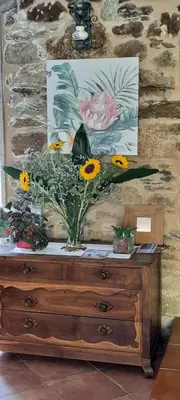 a vase of flowers sitting on top of a dresser at A Quinta Das Maceiras in San Miguel de Castro