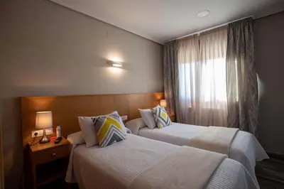 a hotel room with two beds and a window at PENSIÓN CASA ANTONIO in Pantón