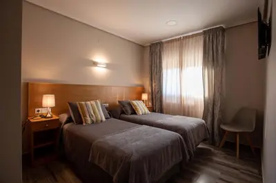a hotel room with two beds and a window at PENSIÓN CASA ANTONIO in Pantón