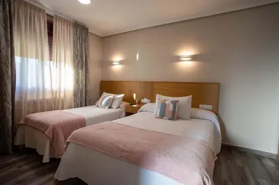 a hotel room with two beds and a window at PENSIÓN CASA ANTONIO in Pantón