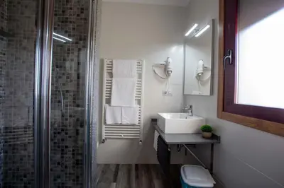a bathroom with a sink and a shower with towels at PENSIÓN CASA ANTONIO in Pantón