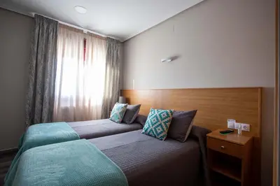 a hotel room with two beds and a window at PENSIÓN CASA ANTONIO in Pantón
