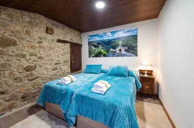 a bedroom with a blue bed in a stone wall at Casa Pion in Sober