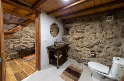 a stone bathroom with a toilet and a stone wall at Casa Pion in Sober