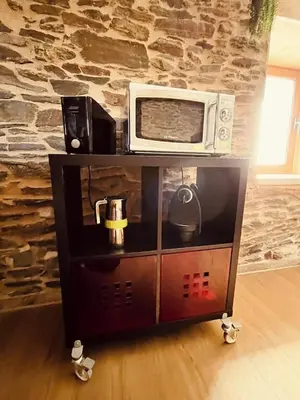 a microwave sitting on top of a stand next to a wall at Casa rural entre Santiago Compostela y La Coruña in Ordes