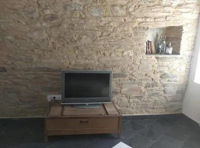 a television on a wooden table in front of a stone wall at casa ferreirua in Ferreirúa