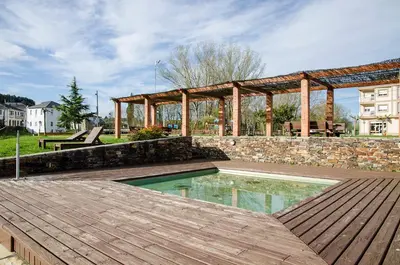 a swimming pool with a wooden deck and a stone wall at casa ferreirua in Ferreirúa