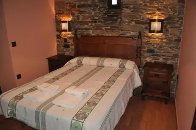 a bedroom with a bed and two lights on the wall at APARTAMENTOS RURALES CASTRO DE VILAOSENDE in Ribadeo