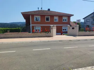a red house on the side of a street at Apartamentos turísticos Lemos in Pedrouzo
