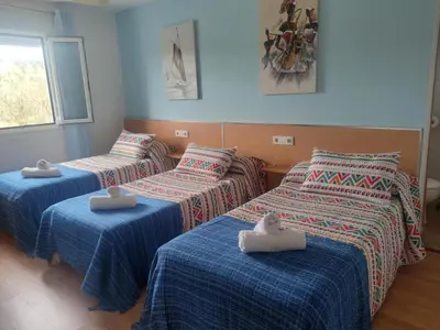 three beds with towels on them in a room at Apartamentos turísticos Lemos in Pedrouzo