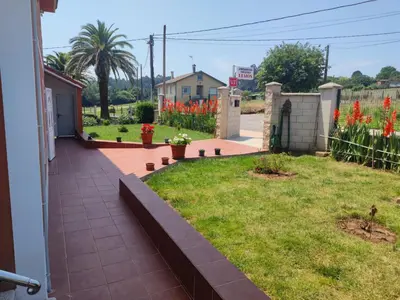 a garden with red flowers and a fence at Apartamentos turísticos Lemos in Pedrouzo