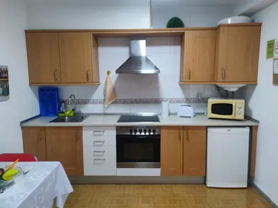 a kitchen with wooden cabinets and a stove top oven at Apartamentos turísticos Lemos in Pedrouzo