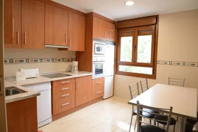 a kitchen with wooden cabinets and a table with chairs at El Mirador De Limes in Cangas del Narcea