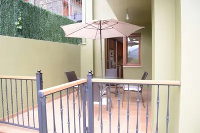a porch with a table and chairs and an umbrella at El Mirador De Limes in Cangas del Narcea