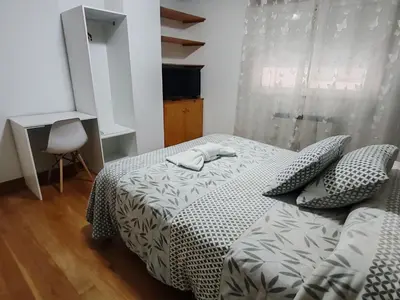 a bedroom with a bed and a chair and a window at Apartamentos Shalom Ribadeo in Ribadeo