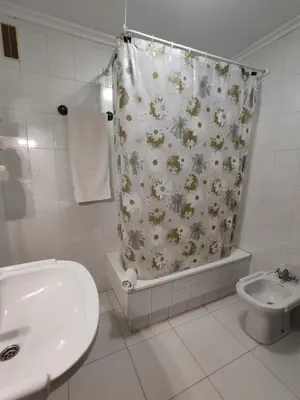 a bathroom with a shower curtain with a toilet and a sink at Apartamentos Shalom Ribadeo in Ribadeo