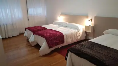 a hotel room with two beds and two lamps at Apartamentos Shalom Ribadeo in Ribadeo