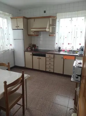a kitchen with a refrigerator and a table in it at Casa familiar con finca privada (Orolterra) in Viveiro