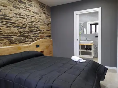 a bedroom with a bed and a stone wall at Apartamentos turísticos o palomar in Villalba
