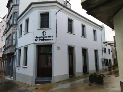 a white building with a sign on the front of it at Apartamentos turísticos o palomar in Villalba