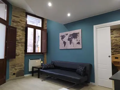a living room with a black couch against a blue wall at Apartamentos turísticos o palomar in Villalba