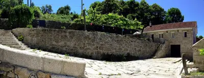 a stone retaining wall next to a building with stairs at QUINTA do SOUTO BARCIADEMERA in Barciademera