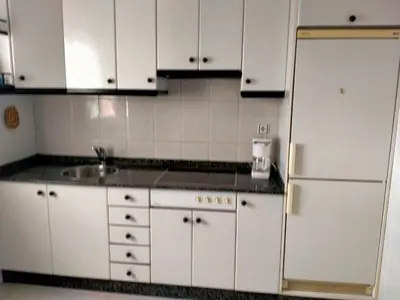 a kitchen with white cabinets and a refrigerator at Vivienda uso turistico Los Nogales in Foz