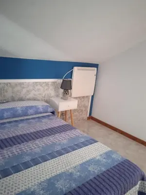 a bedroom with two beds and a table with a lamp at Vivienda uso turistico Los Nogales in Foz
