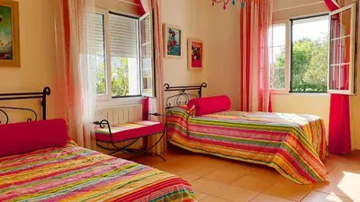 a room with two beds and two chairs and windows at Casa de Pepa en Ribadeo in Ribadeo
