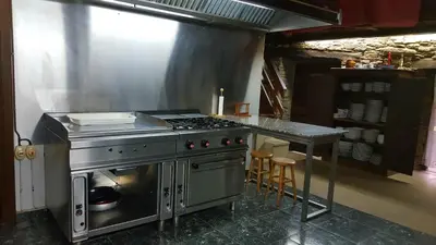 a kitchen with a stove and a table with stools at Casa Berdeal in Santa María