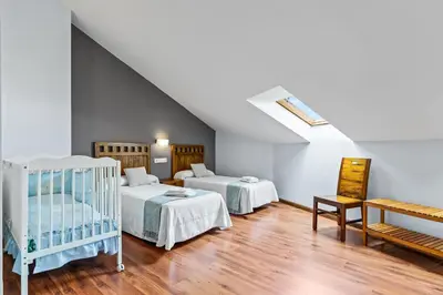 a attic room with two beds and a crib at Apartamentos Turisticos As Cetareas in Rinlo