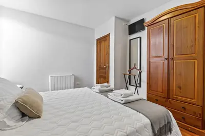 a bedroom with a large bed and a wooden cabinet at Apartamentos Turisticos As Cetareas in Rinlo