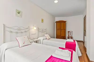 a bedroom with two white beds with pink accents at Apartamentos Turisticos As Cetareas in Rinlo