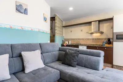 a living room with a couch and a kitchen at Apartamentos Turisticos As Cetareas in Rinlo