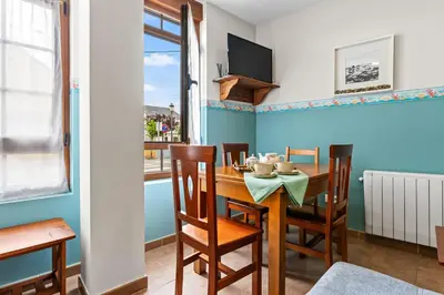 a dining room with a table and chairs and a window at Apartamentos Turisticos As Cetareas in Rinlo
