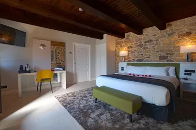 a bedroom with a large bed and a stone wall at Hotel As Torres da Hermida in Monterroso