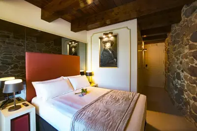 a bedroom with a bed and a portrait of a man at Hotel As Torres da Hermida in Monterroso