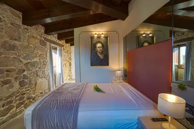 a bedroom with a large bed in a stone wall at Hotel As Torres da Hermida in Monterroso